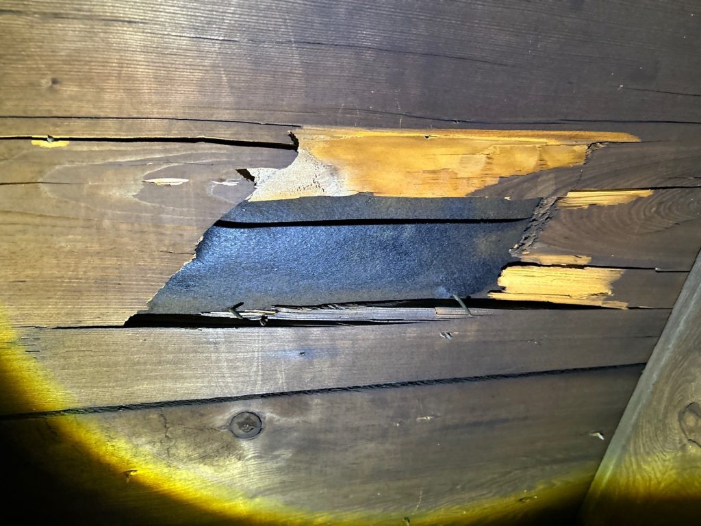 wood panels broken off and tearing inside of a home in need of a new roof
